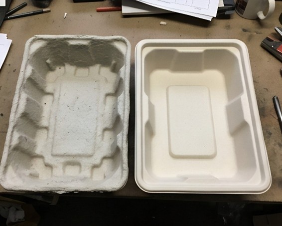Side-by-side comparison of a standard grey molded pulp tray and a modern white precision-formed fiber insert on a cluttered industrial workbench.