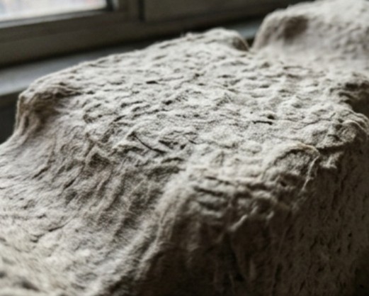 Extreme macro close-up of molded pulp fiber surface showing natural imperfections and recycled material randomness.